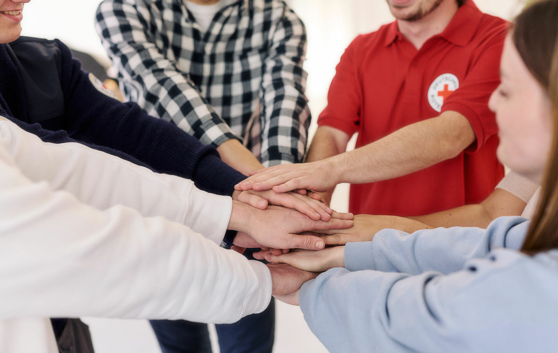 Symbolfoto Mitarbeitende vom DRK legen ihre Hände übereinander Symbolfoto Mitarbeitende vom DRK legen ihre Hände übereinander